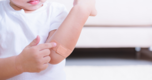 A child pointing to the adhesive bandage on their elbow
