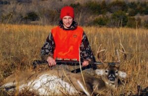 A young man sitting behind the animal he hunted.
