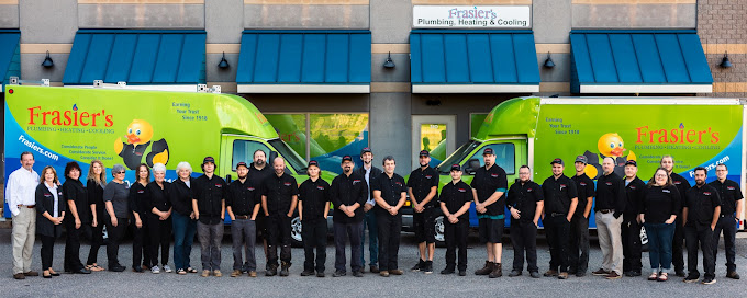 Frasiers team members dressed in black standing in front of two Fraiser's green trucks.