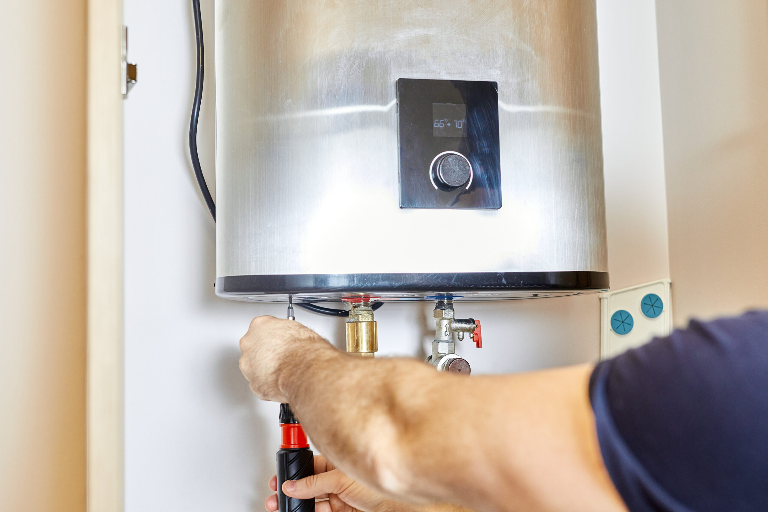 Technician servicing connections below a wall-mounted water heater